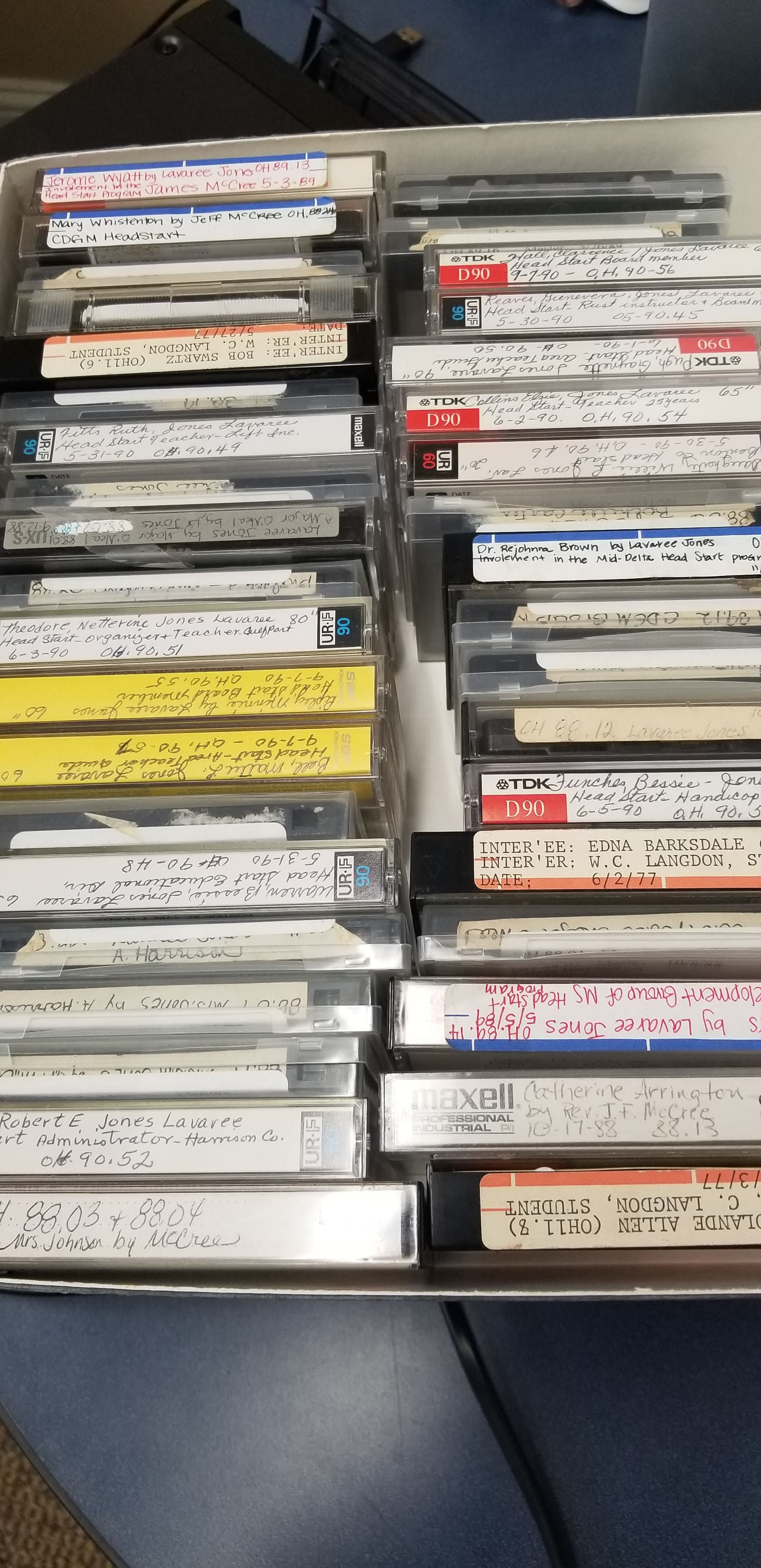 A box of labeled cassette tapes containing oral history recordings.