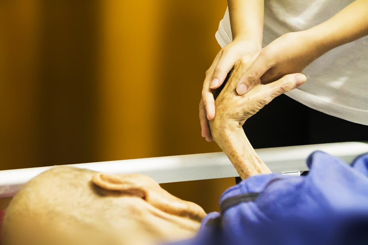 ภาพระยะใกล้ของมือที่จับกันระหว่างการดูแลสนับสนุนในโรคร้ายแรง